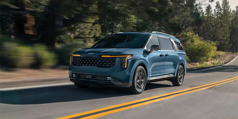 A 2025 Kia Carnival driving down a wooded road near Orangeburg, SC