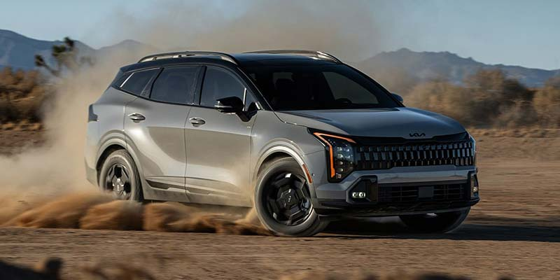 A 2026 Kia Sportage driving through sandy terrain