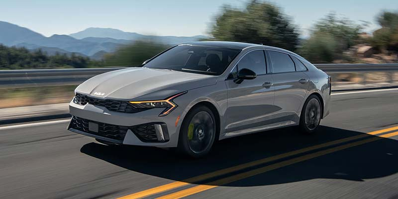 A 2026 Kia K5 driving down a road